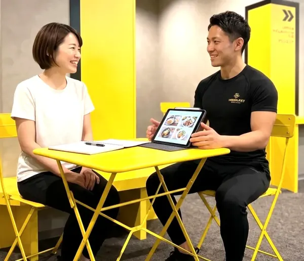トレーナーがタブレットで食事を案内している様子（VISION24）